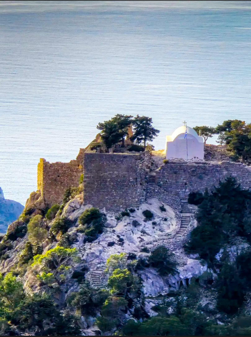 Monolithos castle perched on a steep rock pinnacle at sunset on the Rhodes coast