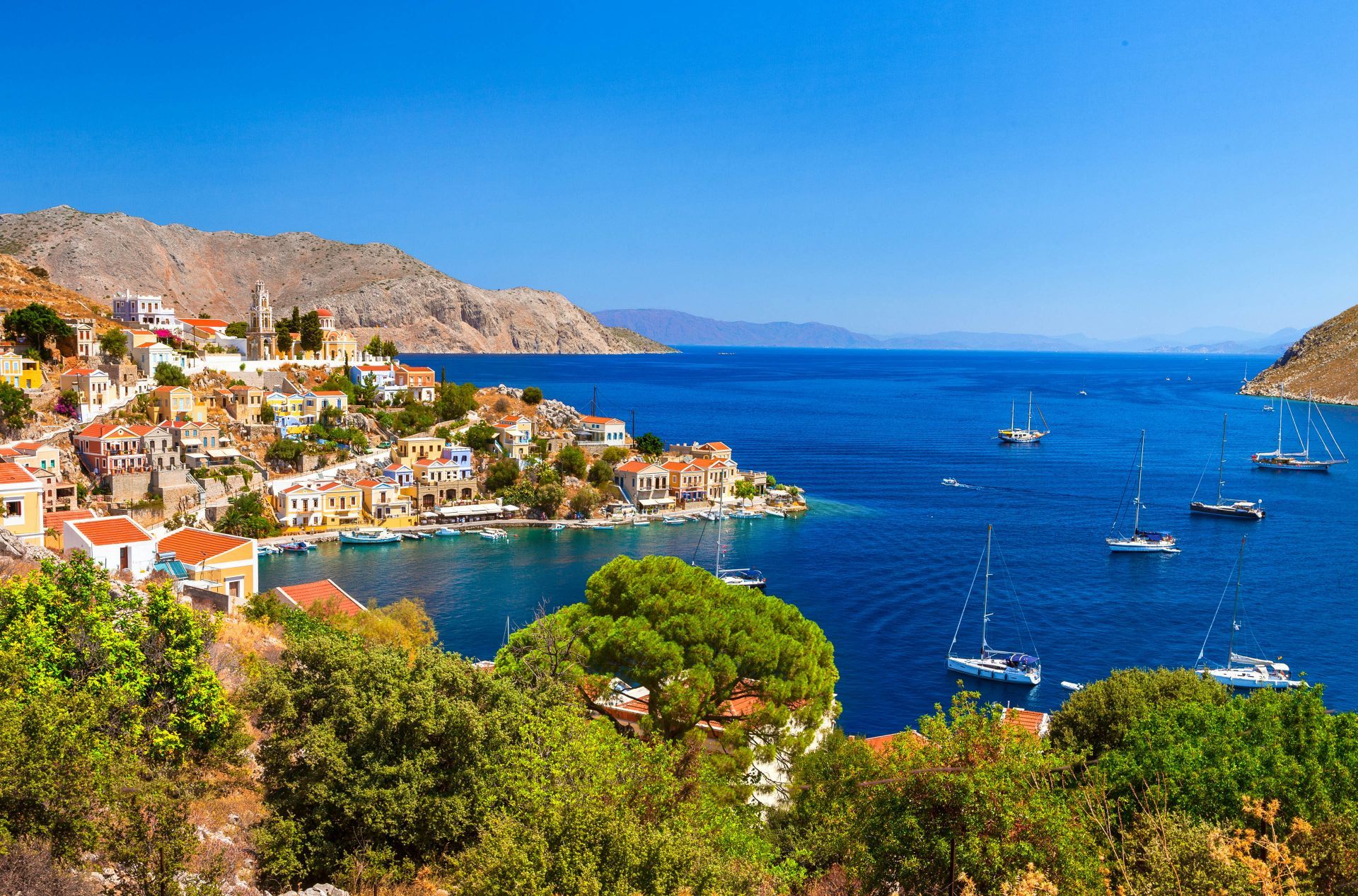 Colourful pastel neoclassical mansions rising above the harbour of Symi island near Rhodes